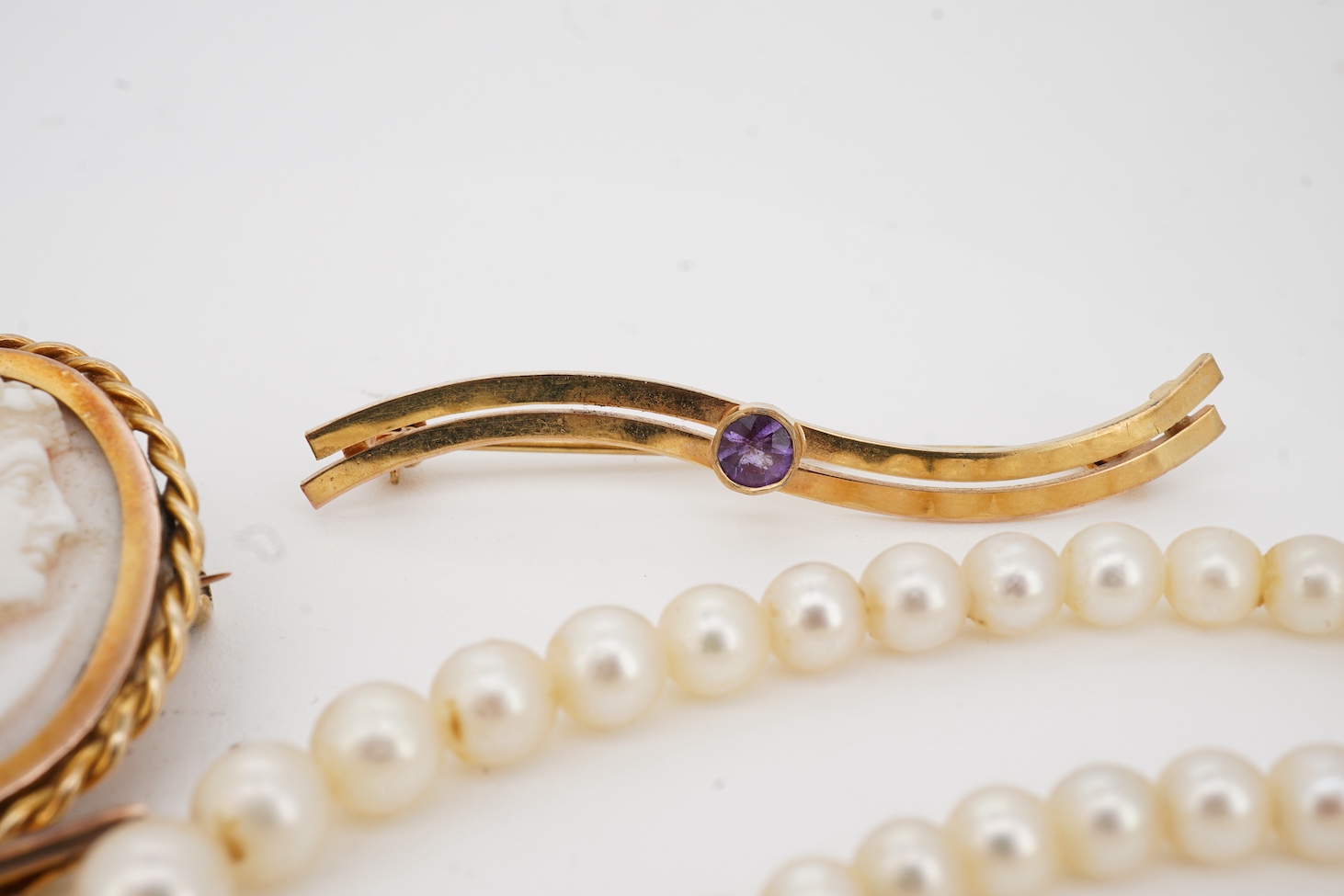 A 9ct owl bar brooch, with cabochon eyes, 50mm, a 1960's 9ct gold and amethyst set bar brooch, an 18ct and amethyst set bar brooch, a cameo brooch(a.f.) and a cultured pearl necklace with 9ct gold clasp.